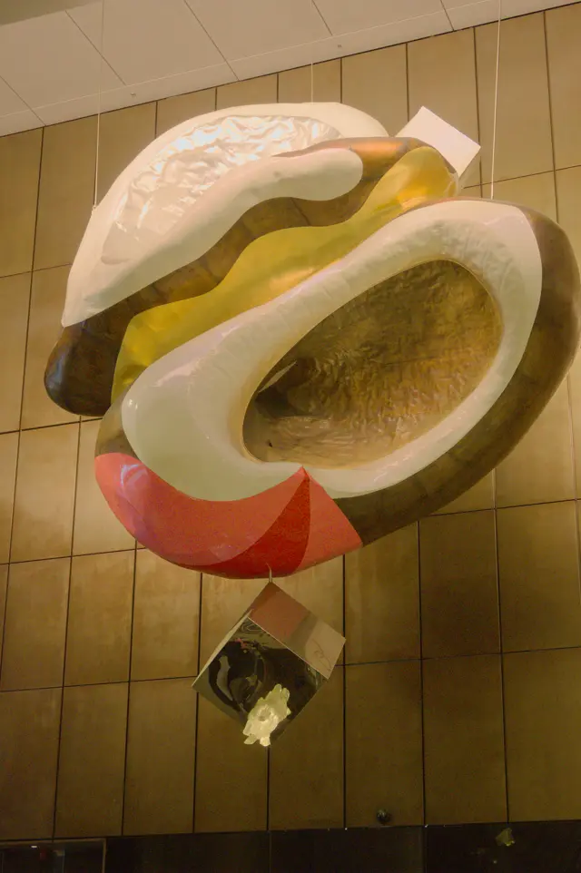 Art installation at the Martin Place metro station. Big white and dark-gold brain-shaped object with yellow and red colored areas, with a cube containing some animal skull looking thing hanging from underneath.