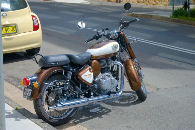 A classic looking Royal Enfield bike parked on the side of the road.