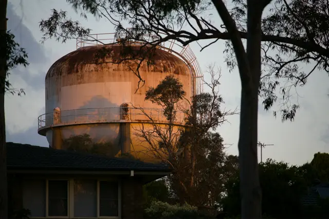 Rusty large water tank reflecting sunset golden hour lights
