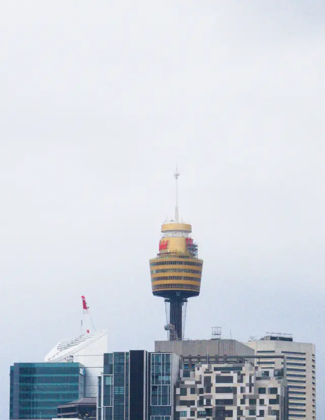 Westfield tower in Sydney, protuding atop a clump of buildings with a gray sky as background